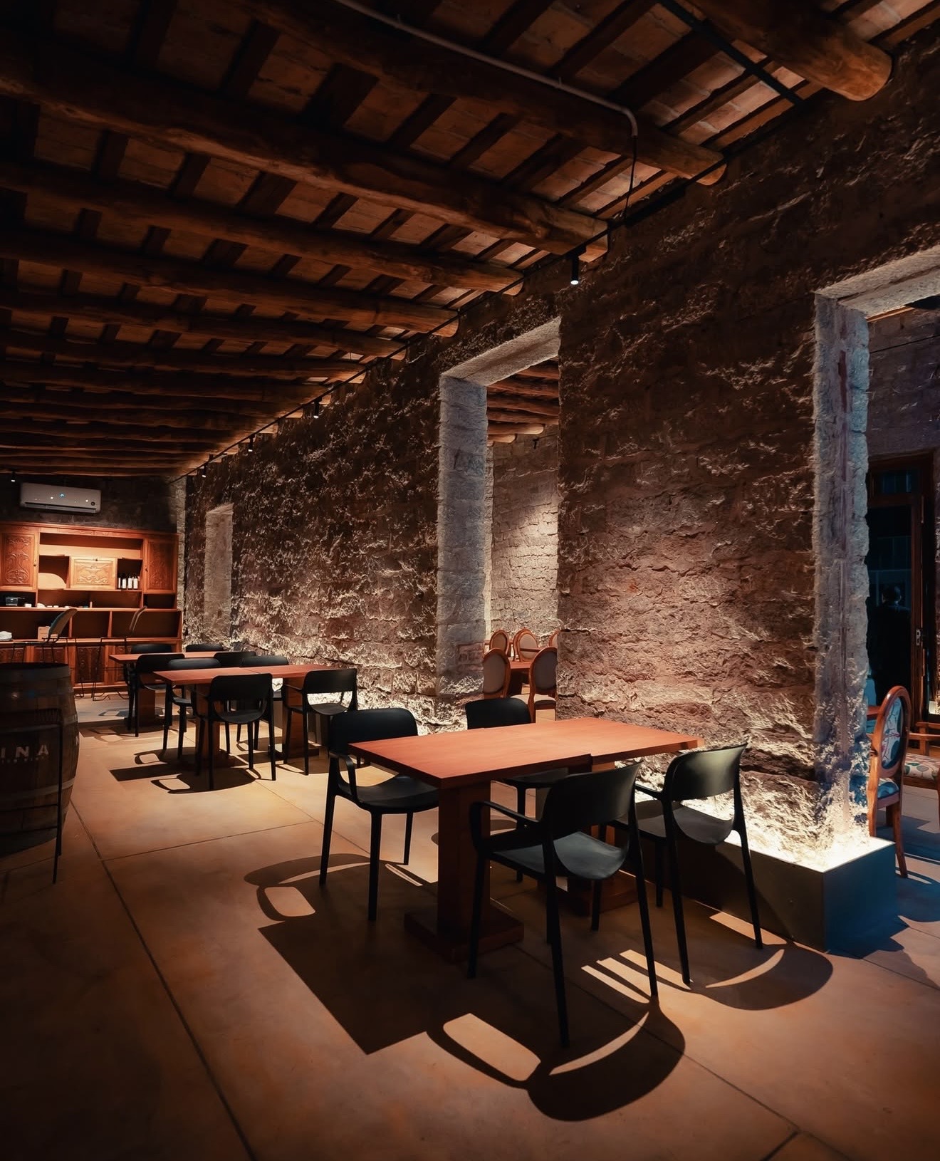 Salón interior de paredes de piedra con mesas de madera